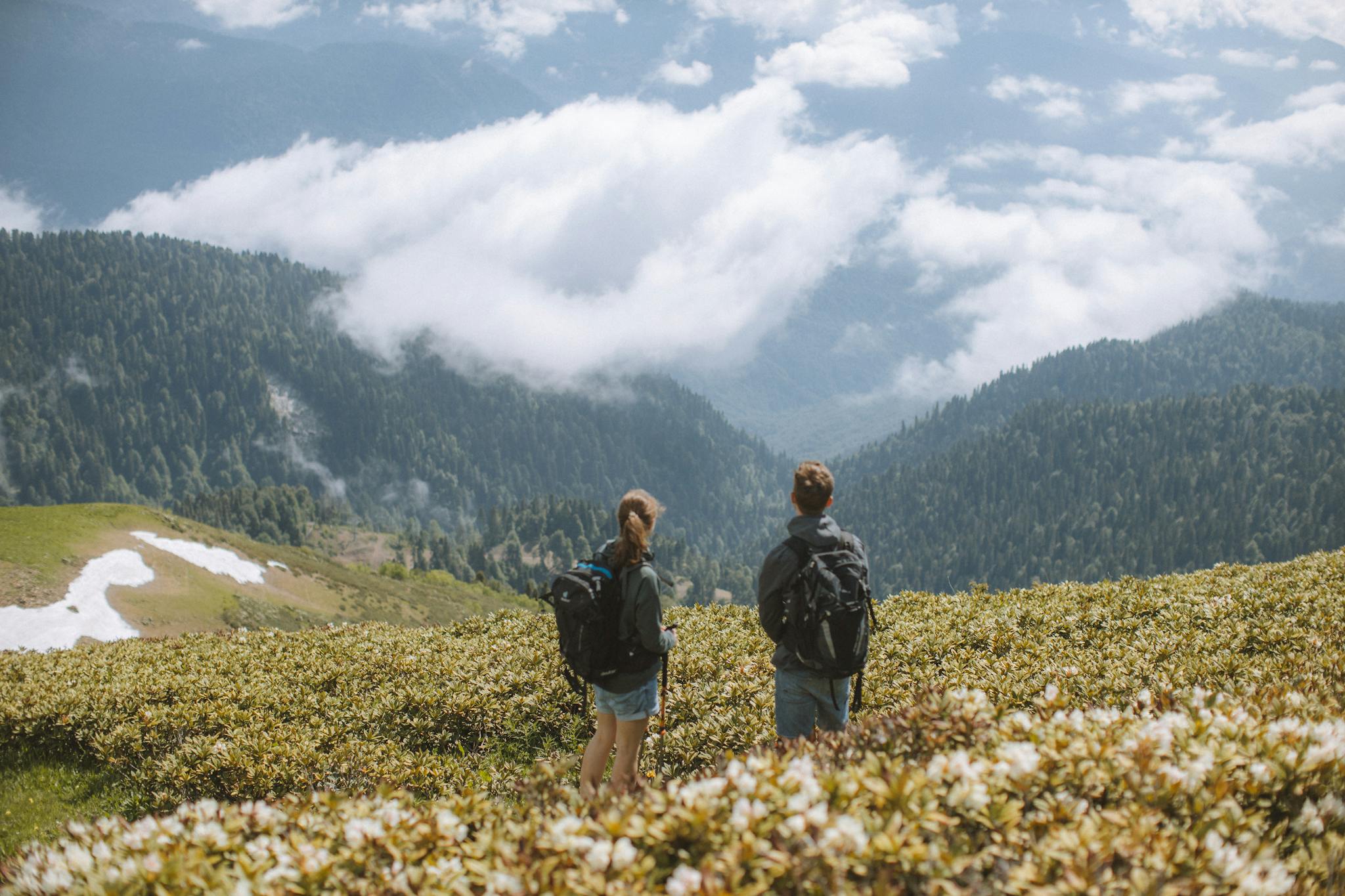 Two hikers with backpacks admire a stunning mountain landscape. Perfect for travel and adventure themes.